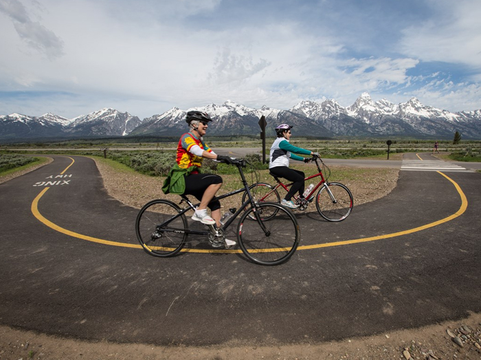 bikers on path in front of Tetons